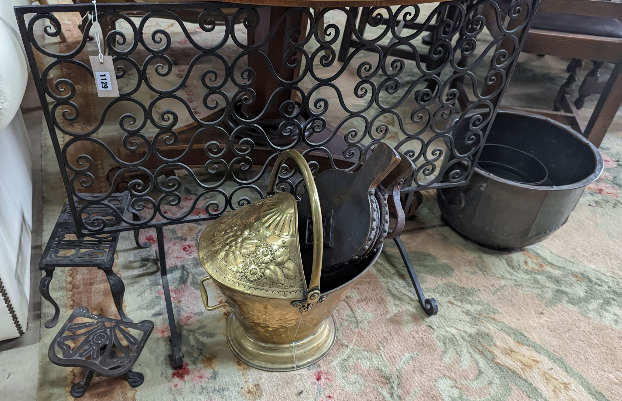 A wrought iron scroll work firescreen, width 95cm, a Dutch embossed brass scuttle, two trivets, coal bin and assorted metalware